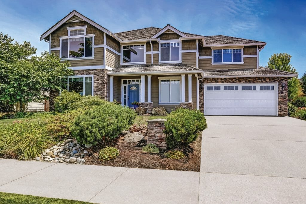 A house with a white shaker panel garage door installed.